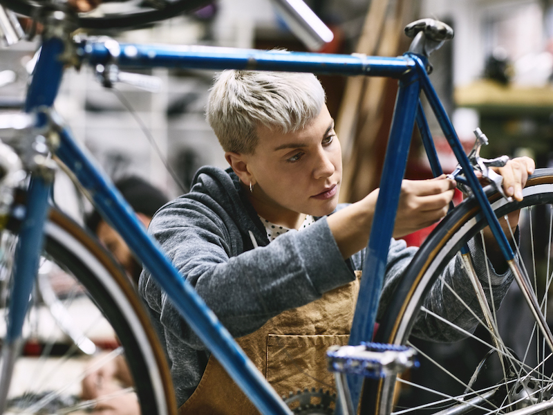 An employee in a bike shop looks competent and focused while she repairs a bicycle